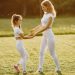 A mother and daughter in matching activewear enjoy playful bonding at the park during sunset.