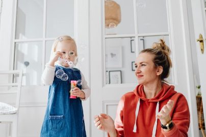 A joyful moment of a mother and daughter playing with bubbles indoors.