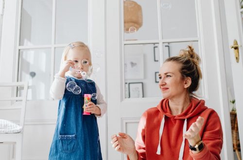 A joyful moment of a mother and daughter playing with bubbles indoors.